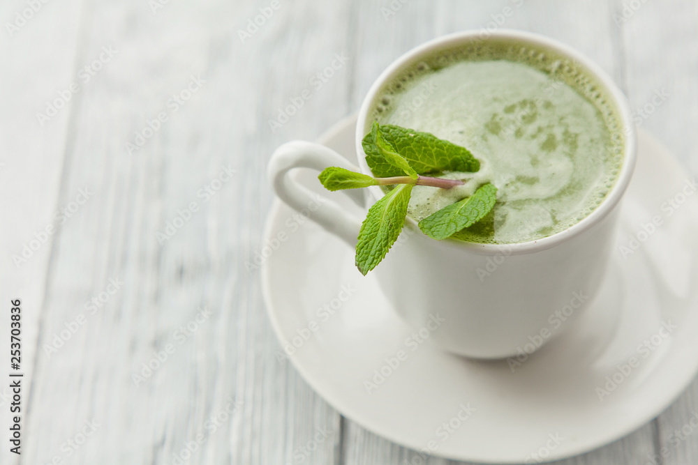 cup of hot matcha green tea with branch of mint on a grey background,close up cup of hot matcha green tea with branch of mint on a grey background,close up
