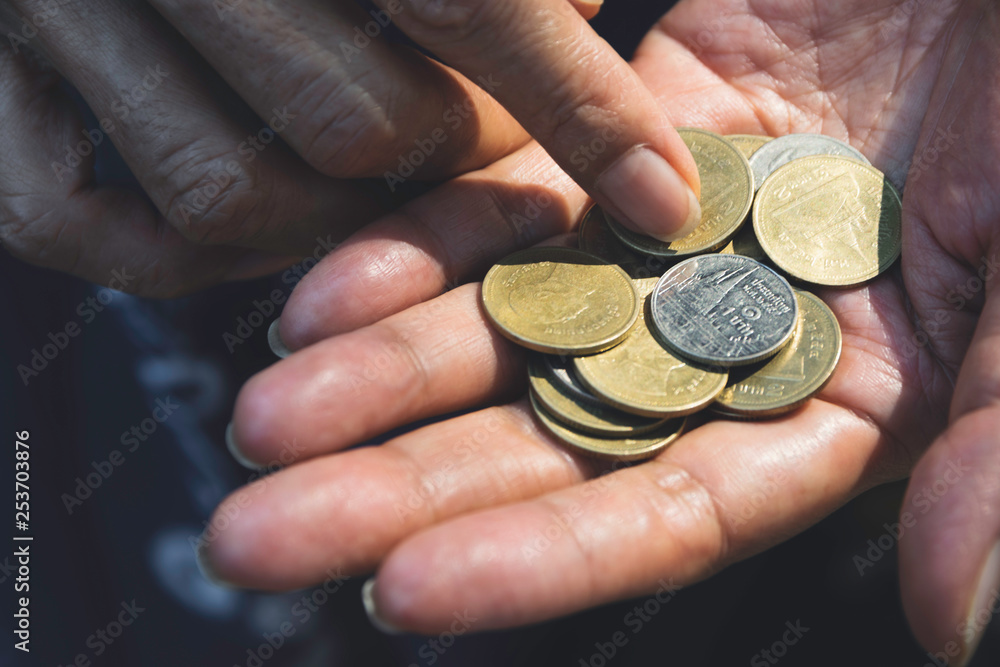Fototapeta premium Close up hand holding coins for saving concept on dark background.