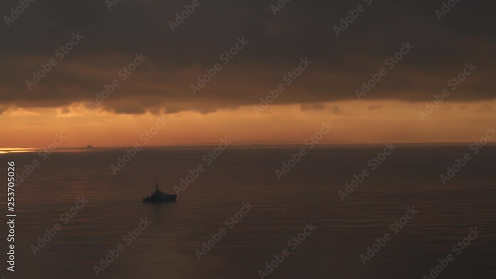 Wide aerial view of a Royal Navy Warship sailing on a calm sea at sunrise. Wide aerial view of a Royal Navy Warship sailing on a calm sea at sunrise.