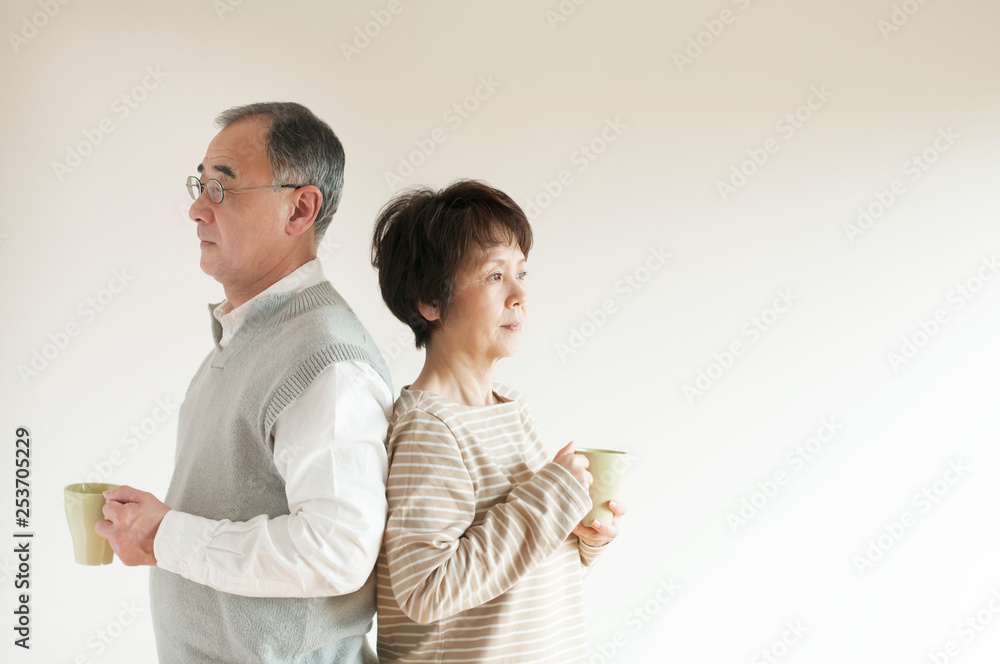 コーヒーを持ち背中合わせに立つシニア夫婦 コーヒーを持ち背中合わせに立つシニア夫婦