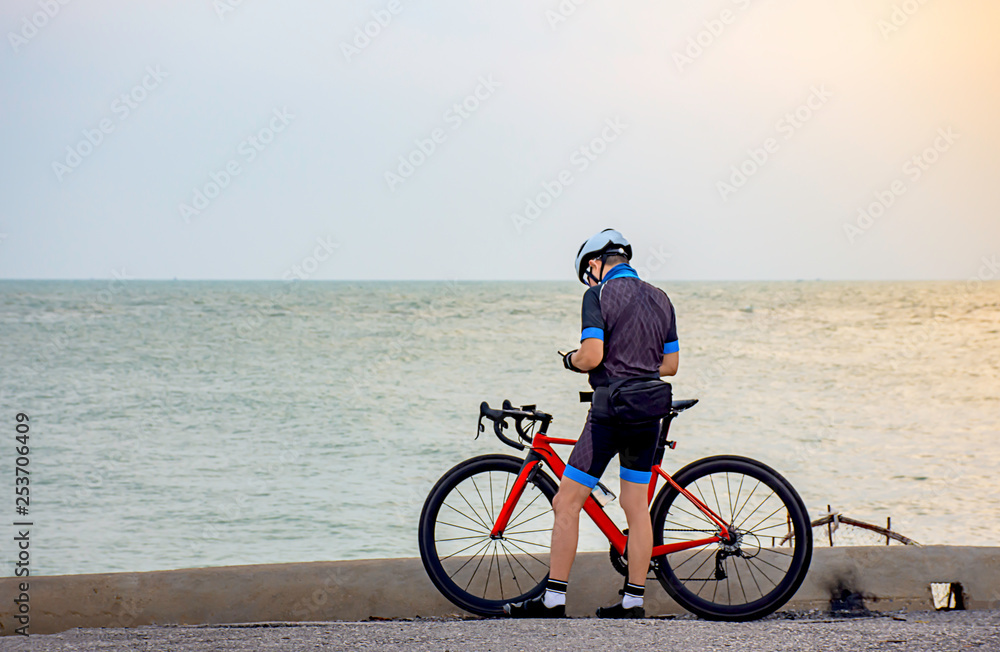 Fototapeta premium Man and a bicycle parked on the road by the sea In the morning