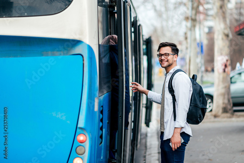 Принти на полотні Handsome smiling young man getting into bus.