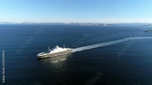 Aerial footage of a ferry sailing forward with snowy mountains in the background. photo