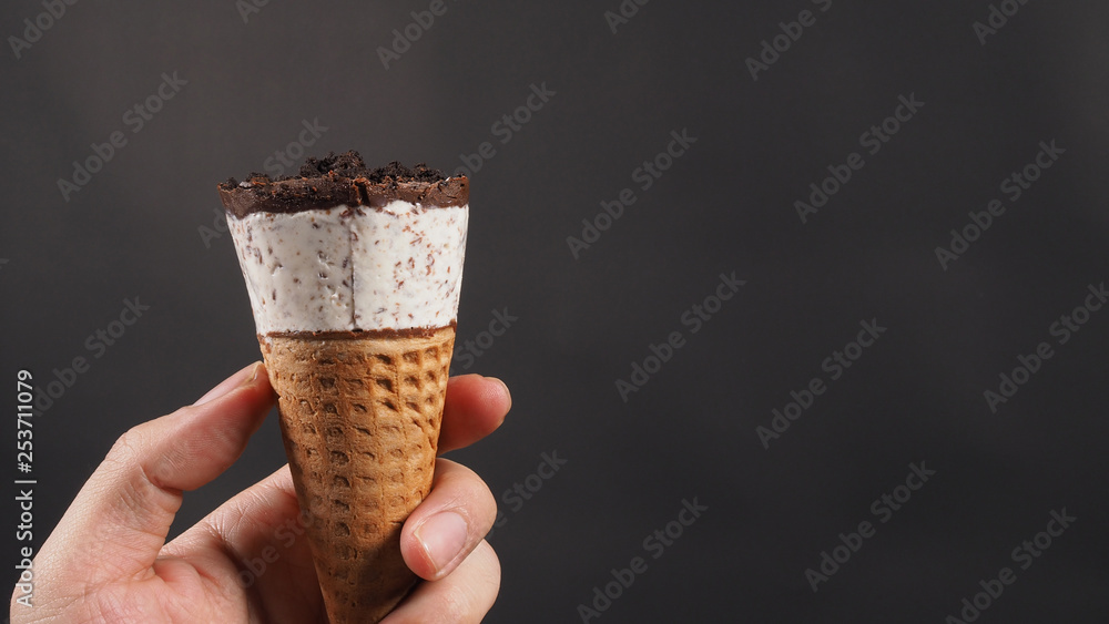 hand is holding ice cream cone with black background. hand is holding ice cream cone with black background.