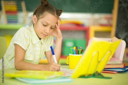 Portrait of cute teen girl doing homework in her room