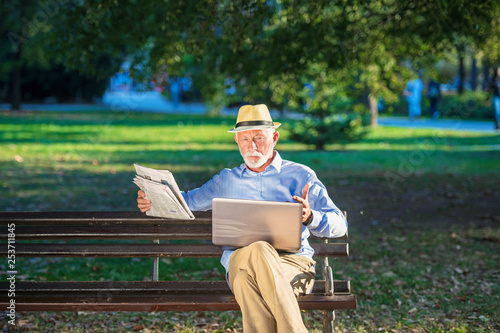 Senior man using laptop computer at rest in the park outdoors