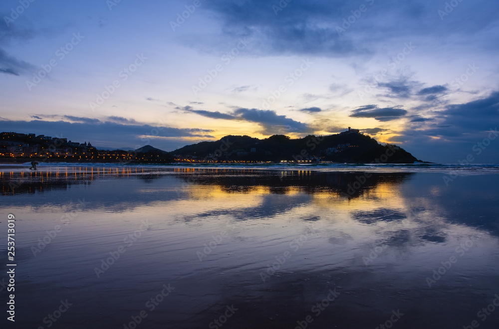 Lights of the city and Mount Igueldo are reflected in the beach of La Concha city of Donostia