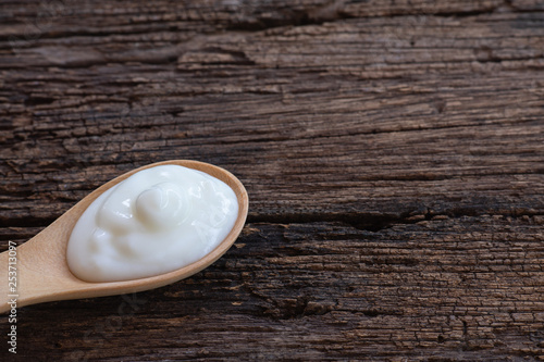 Natural homemade plain organic yogurt in wood spoon on wood texture background