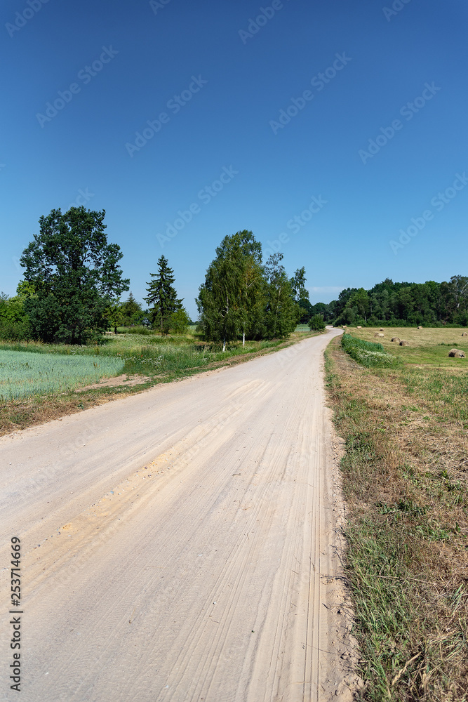 Fototapeta premium Dusty gravel road in summer afternoon.
