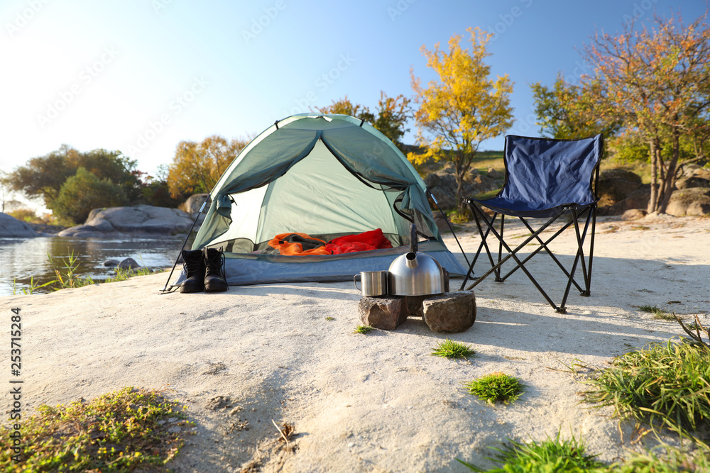Camping equipment near tent with sleeping bag outdoors