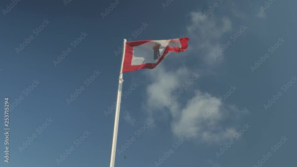 The city flag of Gijón (Asturies, Spain) waving in the wind. Centered below shot, with the blue sky with a few clouds as a background. The city flag of Gijón (Asturies, Spain) waving in the wind. Centered below shot, with the blue sky with a few clouds as a background.