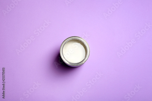 Open paint can on color background, top view