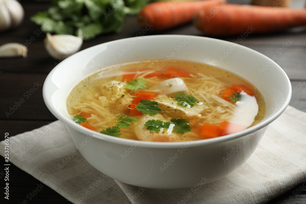 Dish with fresh homemade chicken soup on wooden table