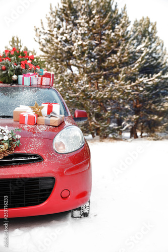 Car with Christmas tree, wreath and gifts in snowy forest on winter day. Space for text © New Africa