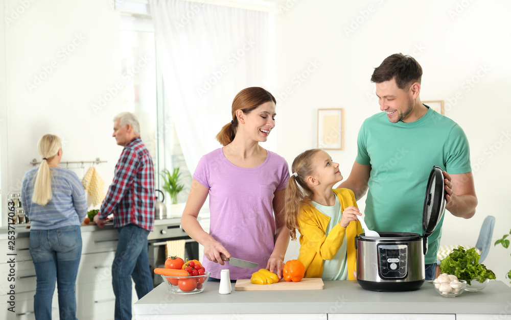 Happy family preparing food with modern multi cooker in kitchen Happy family preparing food with modern multi cooker in kitchen