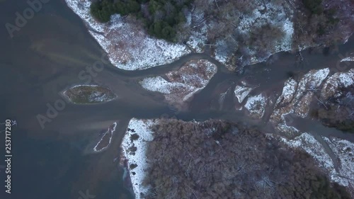 Rising top-down drone footage over a curvy dirty river in a forest. photo