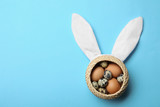 Easter bunny ears and basket with eggs on color background, top view. Space for text