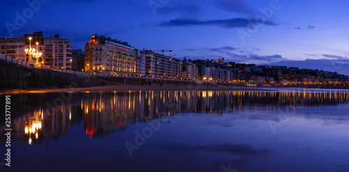 SAN SEBASTIAN, SPAIN - March 06, 2019: The buildings of the city are reflected in the water of La Concha beach in the city of Donostia © poliki