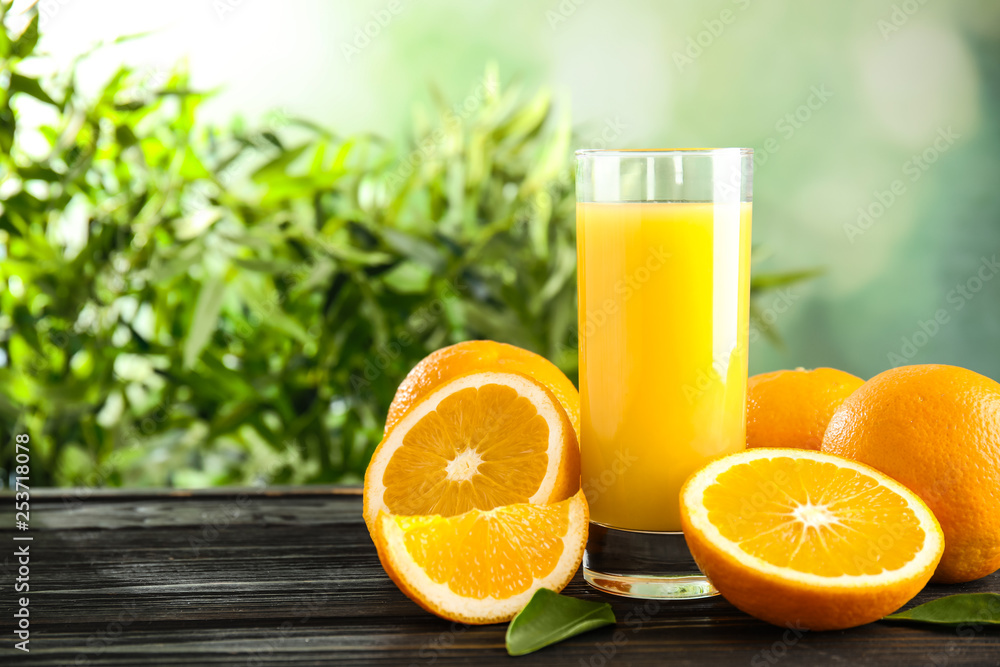 Naklejka premium Glass with orange juice and fresh fruit on wooden table, space for text