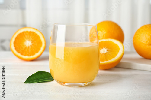 Foto Glass with orange juice and fresh fruit on table