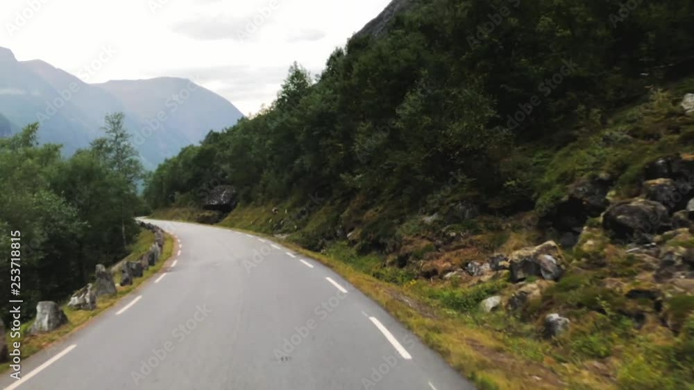 Fast driving down a narrow road in the mountains, first person view, dash cam, mountains rise above the valley, vicinity of Trolls ladder, Trollstigen in Norway, a popular destination in Scandinavia Fast driving down a narrow road in the mountains, first person view, dash cam, mountains rise above the valley, vicinity of Trolls ladder, Trollstigen in Norway, a popular destination in Scandinavia