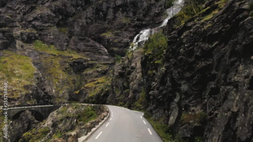 Stigfossen waterfall and bridge at Trolls ladder, Trollstigen in Norway, view from a bus, driving down a narrow mountain road with tight hairpin turns, a popular tourist destination in Norway Stigfossen waterfall and bridge at Trolls ladder, Trollstigen in Norway, view from a bus, driving down a narrow mountain road with tight hairpin turns, a popular tourist destination in Norway