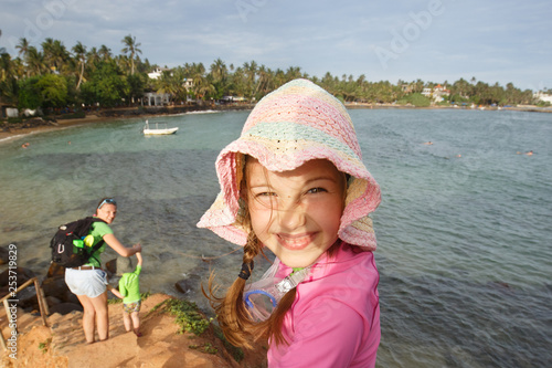 Obraz na płótnie Little girl with a hat on a family hike by the tropical sea. w salonie