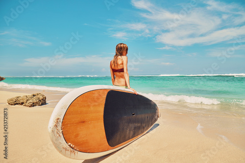 Beautiful surfer girl in bikini with surfboard enjoying on the beach. Summer concept.