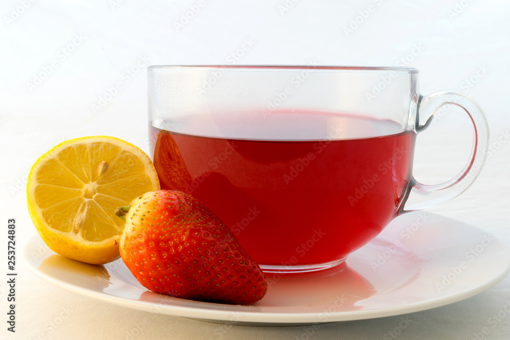 Glass cup of hot aromatic red tea with strawberry and lemon