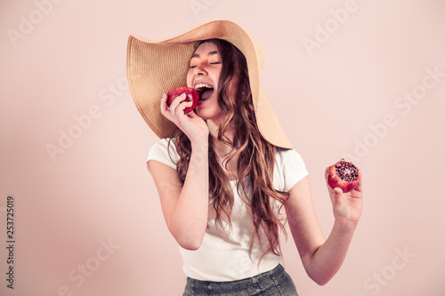 Portrait of a girl in a summer hat with fruit on a colored background