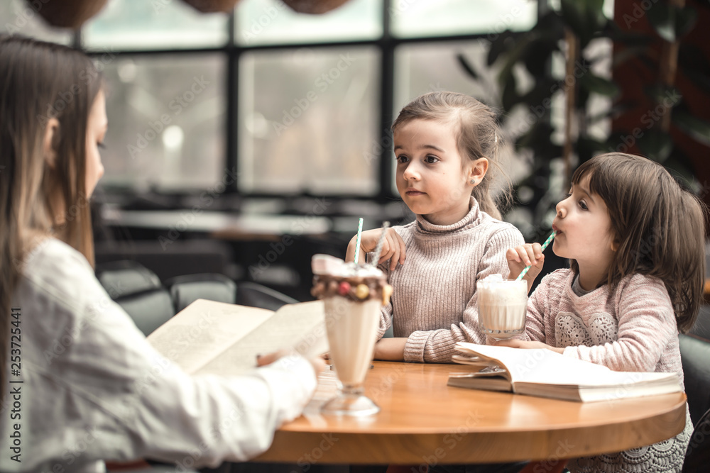 Happy young women mother with children sitting at dinner table and talking in restaurant