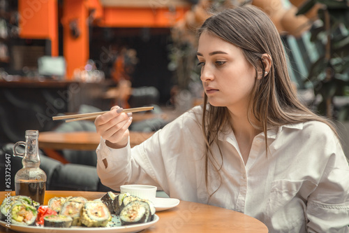 Young Woman eating and enjoying fresh sushi