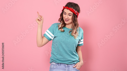Portrait girl pointing her finger to the side on an isolated pink background
