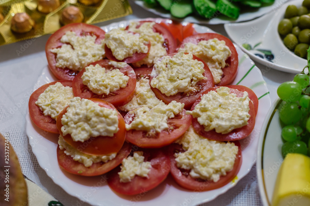 A dish of tomato with cheese and garlic on a white plate. A dish of tomato with cheese and garlic on a white plate.