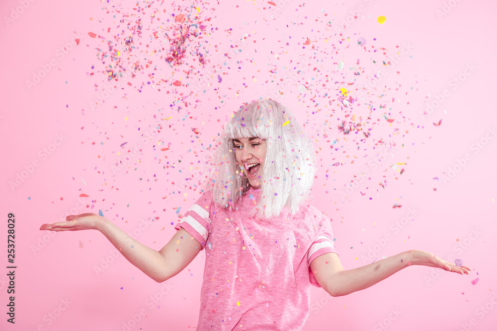 Obraz premium Funny Girl with silver hair gives a smile and emotion on pink background. Young woman or teen girl with confetti