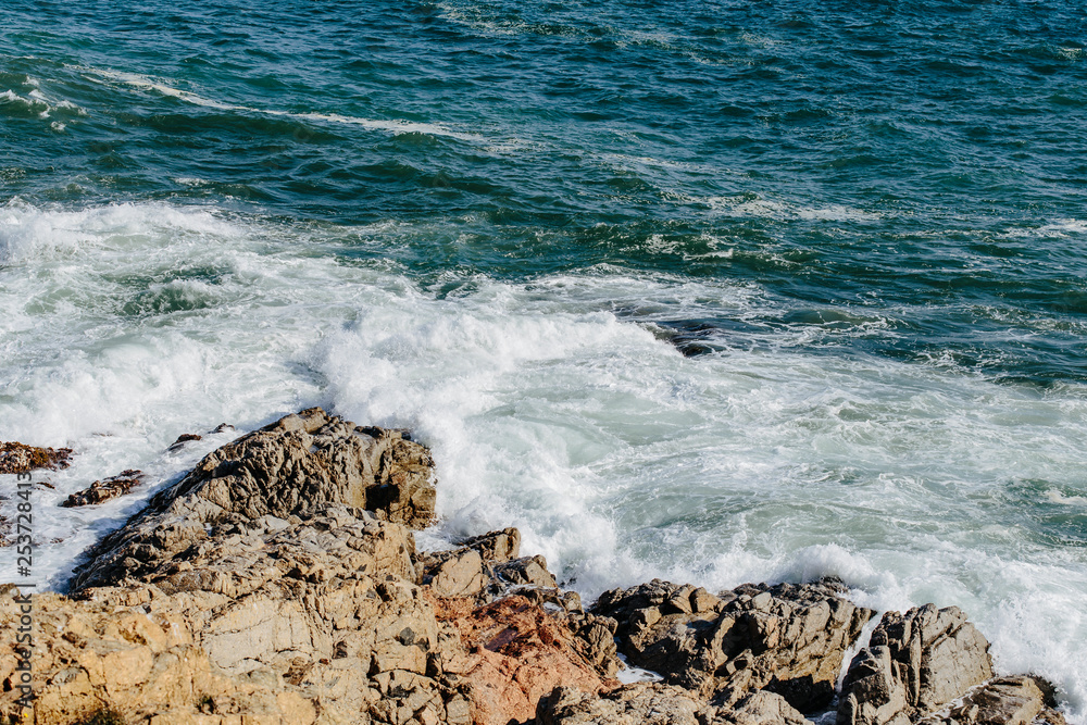 Mediterranean Sea water waves crashing on the shore rocks