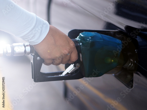 Close up hand of man pumping gasoline fuel in car at gas station. © v.stock