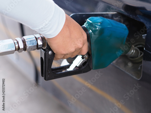 Close up hand of man pumping gasoline fuel in car at gas station.