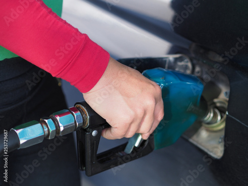 Close up hand of man pumping gasoline fuel in car at gas station.