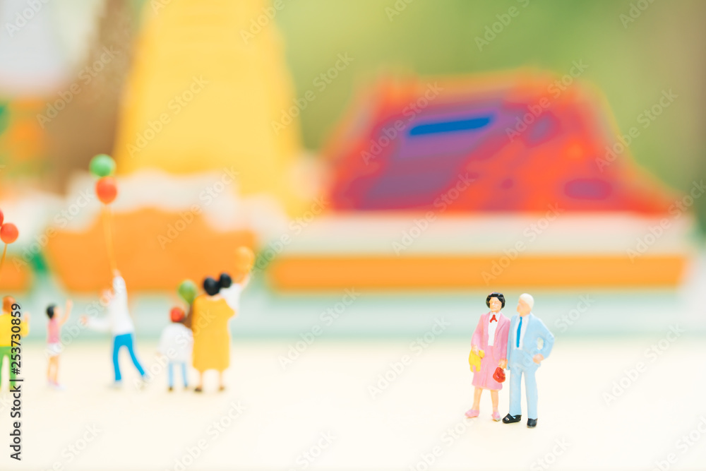 Concepts of unlock retirement planning and family travel. Miniature people: Old couple figure standing in front of temple with others tourist.