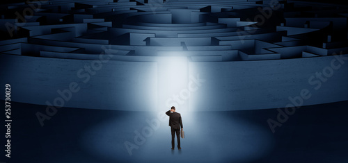 Businessman getting ready to enter a concentric labyrinth with lighted entrance concept  