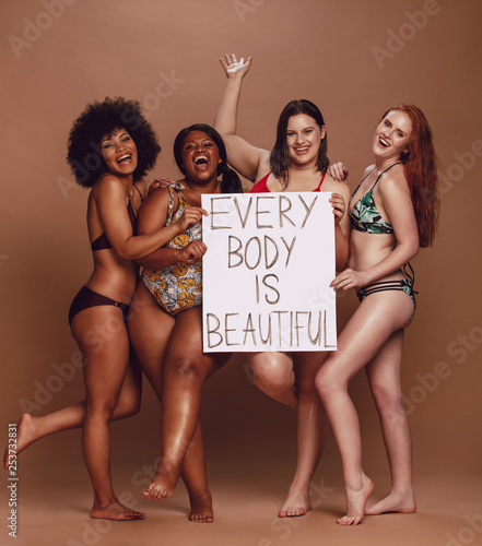 Cheerful female group with every body is beautiful signboard