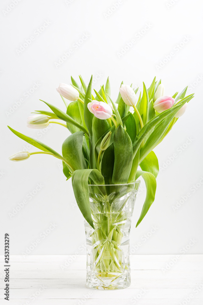 Bouquet of tulips in delicate white and pink color in a transparent crystal vase