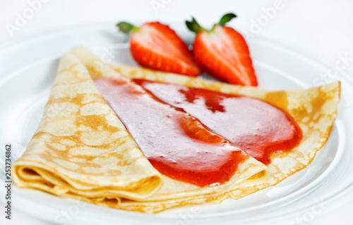 Thin delicious pancake with strawberry on white