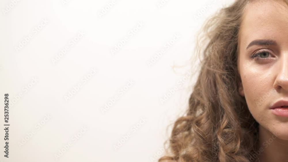 Half face portrait of the gently smiling attractive young girl with silky blond hair on white background Half face portrait of the gently smiling attractive young girl with silky blond hair on white background