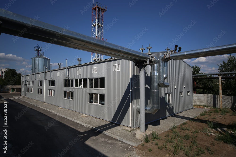 Wide-angle panoramic photo of the newest alternative fuel boiler room with pipes, towers and tanks, on a clear summer day, without people
