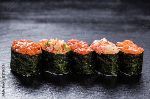 Shrimp, salmon, scallop, tuna gunkanmaki stacked side by side against slate backround photo