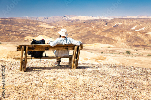 Backpacker tourist sitting desert mountain summit bench landscape.