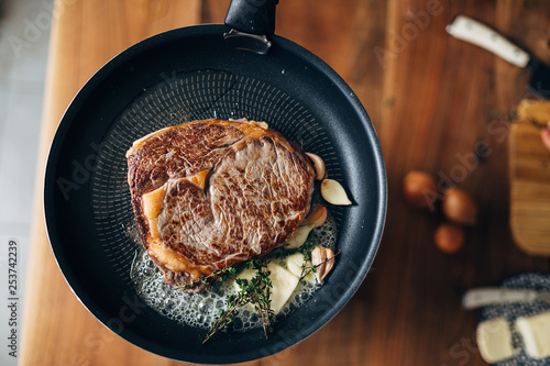 Obraz na płótnie Overhead shot of  ribeye being prepared in a skillet with butter, thyme and garl