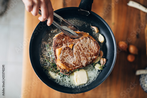 Overhead shot of chef preparing ribeye with butter, thyme and garlic. Keto diet.